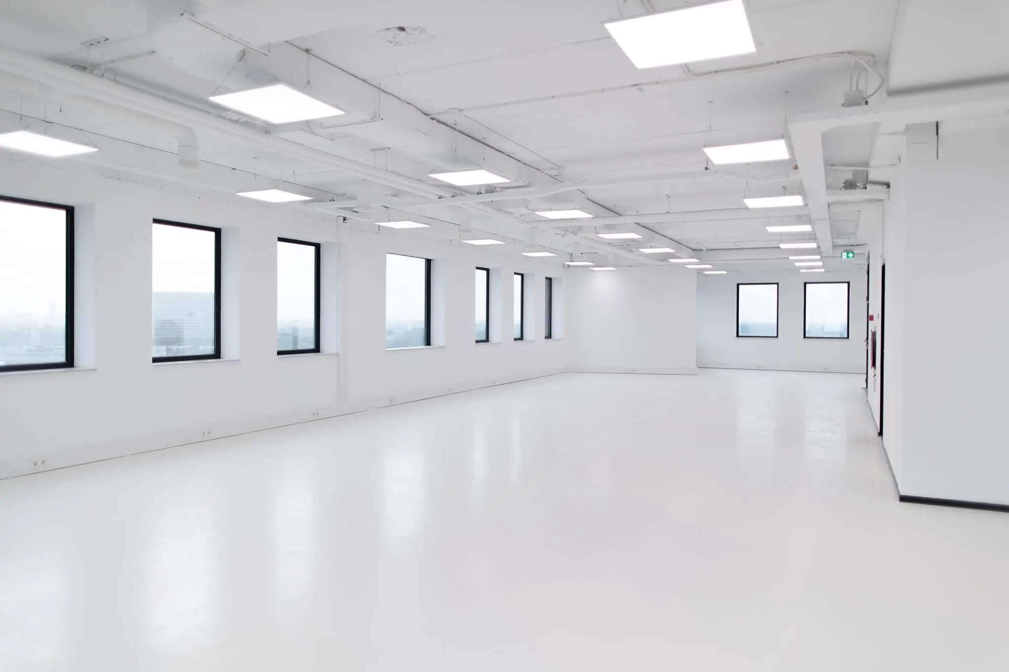 Lichte, lege kantoorruimte in het Rivium Quadrant met grote ramen en plafondverlichting.